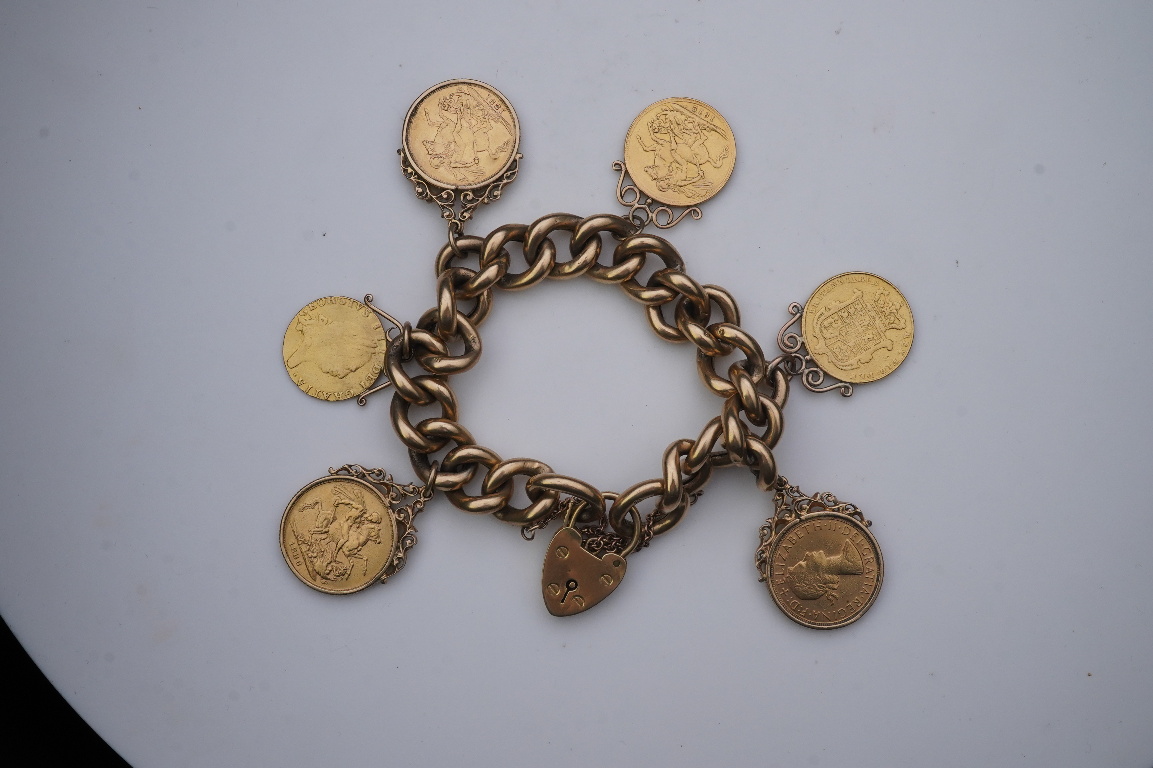 An Edwardian 18ct gold charm bracelet and five gold coin pendants